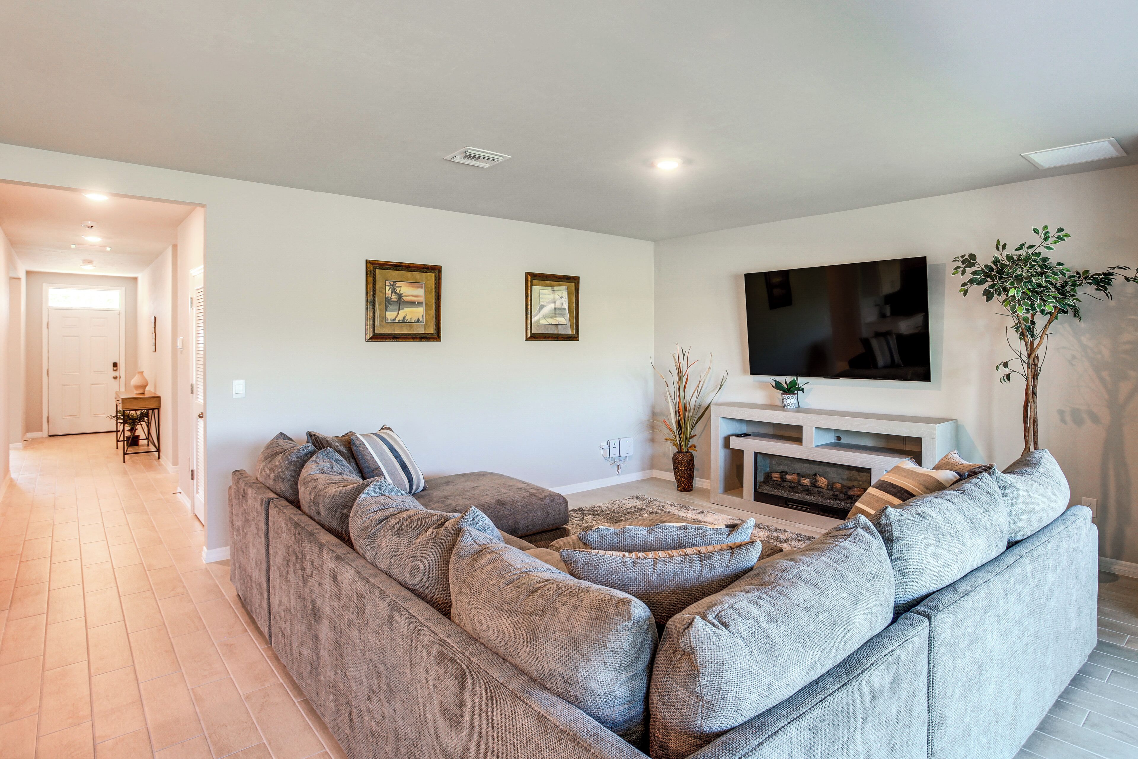 A living room with a large sectional sofa, a flat-screen TV, and a fireplace.