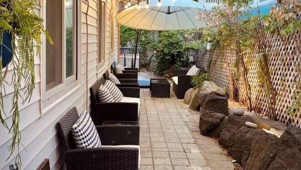 A patio area with wicker furniture, a large umbrella, and a stone pathway. - Hideout Guesthouse (Seoul)