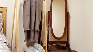 A wooden bed frame with a headboard, a mirror with a wooden frame, and a wooden drying rack with towels. - Hideout Guesthouse (Seoul)