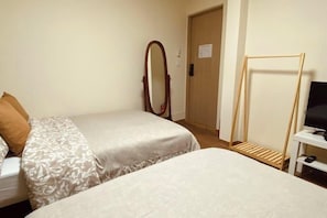 A hotel room with two beds, a mirror, a wooden rack, and a television. - Hideout Guesthouse (Seoul)