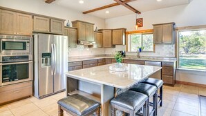 A modern kitchen with stainless steel appliances, wooden cabinets, and a large island with bar stools. - Beautiful 4 bedroom mountain retreat , with stunning views. (Buena Vista)