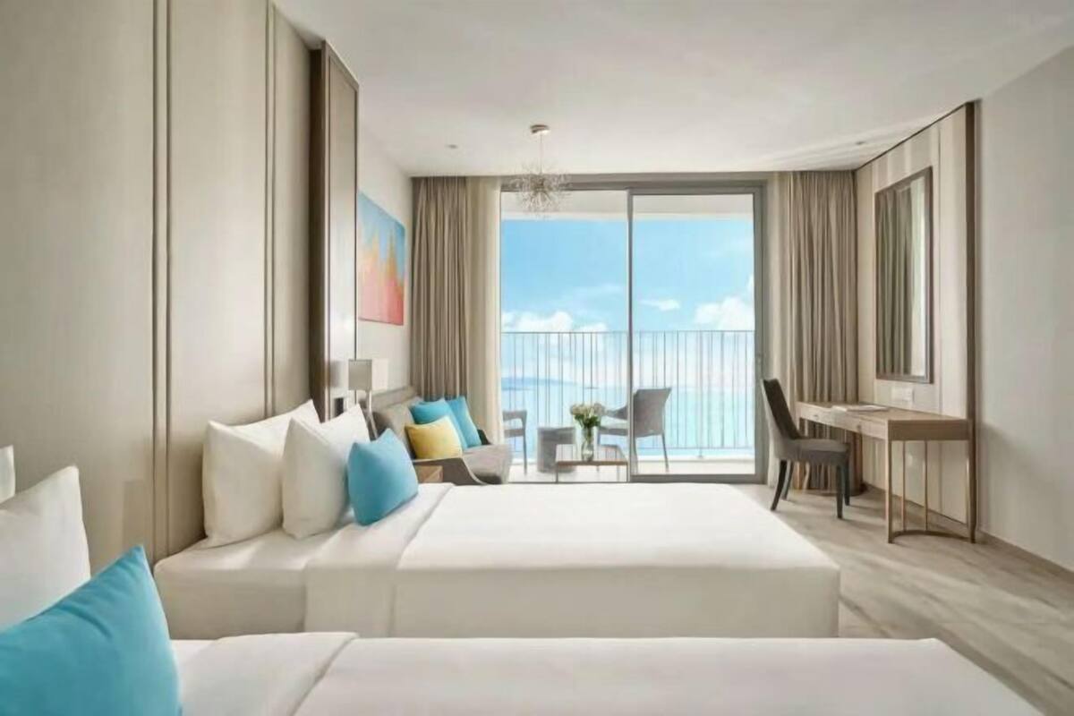 Una camera d'albergo con un letto grande, una scrivania, una sedia e vista mare.