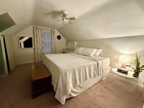 A bedroom with a bed, a nightstand, a lamp, and a ceiling fan.