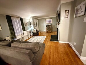 Ein Wohnzimmer mit Sofa, Kamin, Teppich und Fernseher.