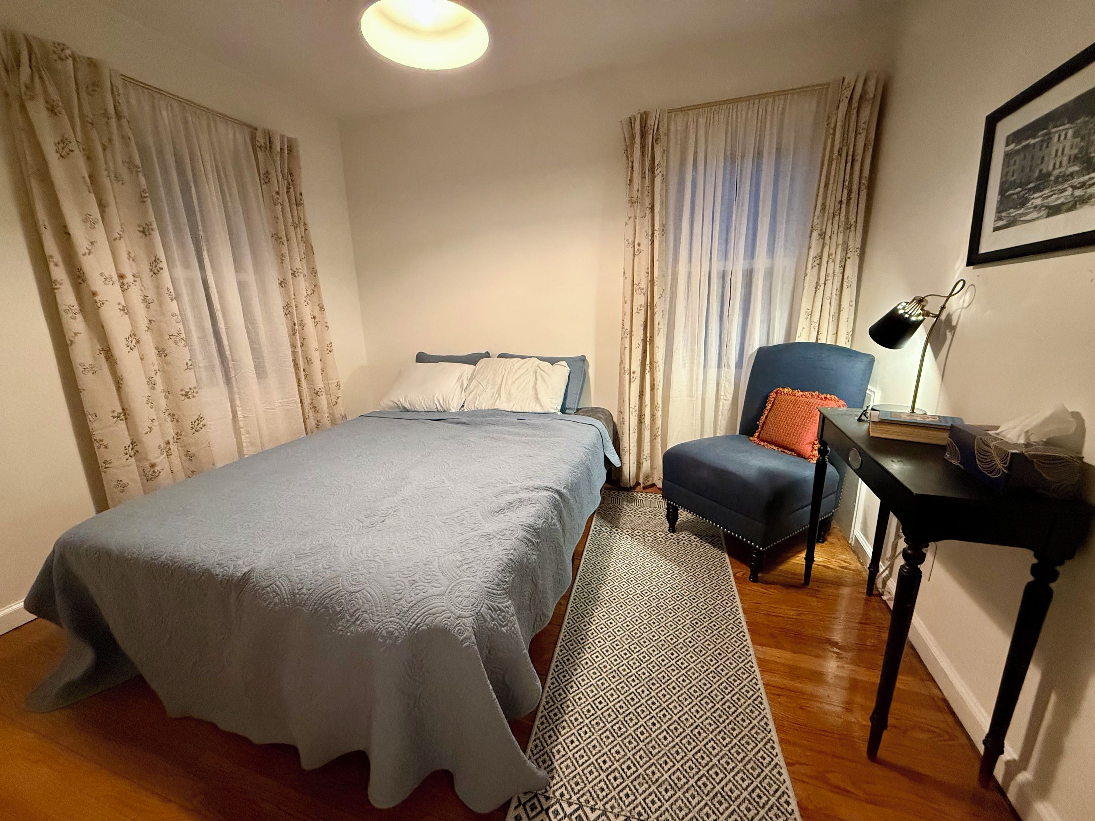A bedroom with a bed, a chair, a desk, and a lamp.