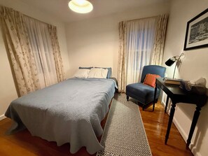 A bedroom with a bed, a chair, a desk, and a lamp.