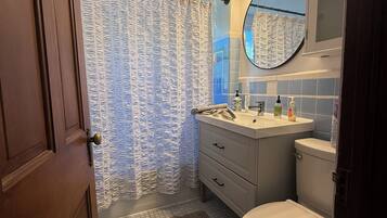 A bathroom with a shower curtain, a sink with a mirror, and a toilet.