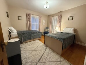 Une chambre d’hôtel avec deux lits, une table de chevet, une chaise, une lampe et un tapis à motifs.