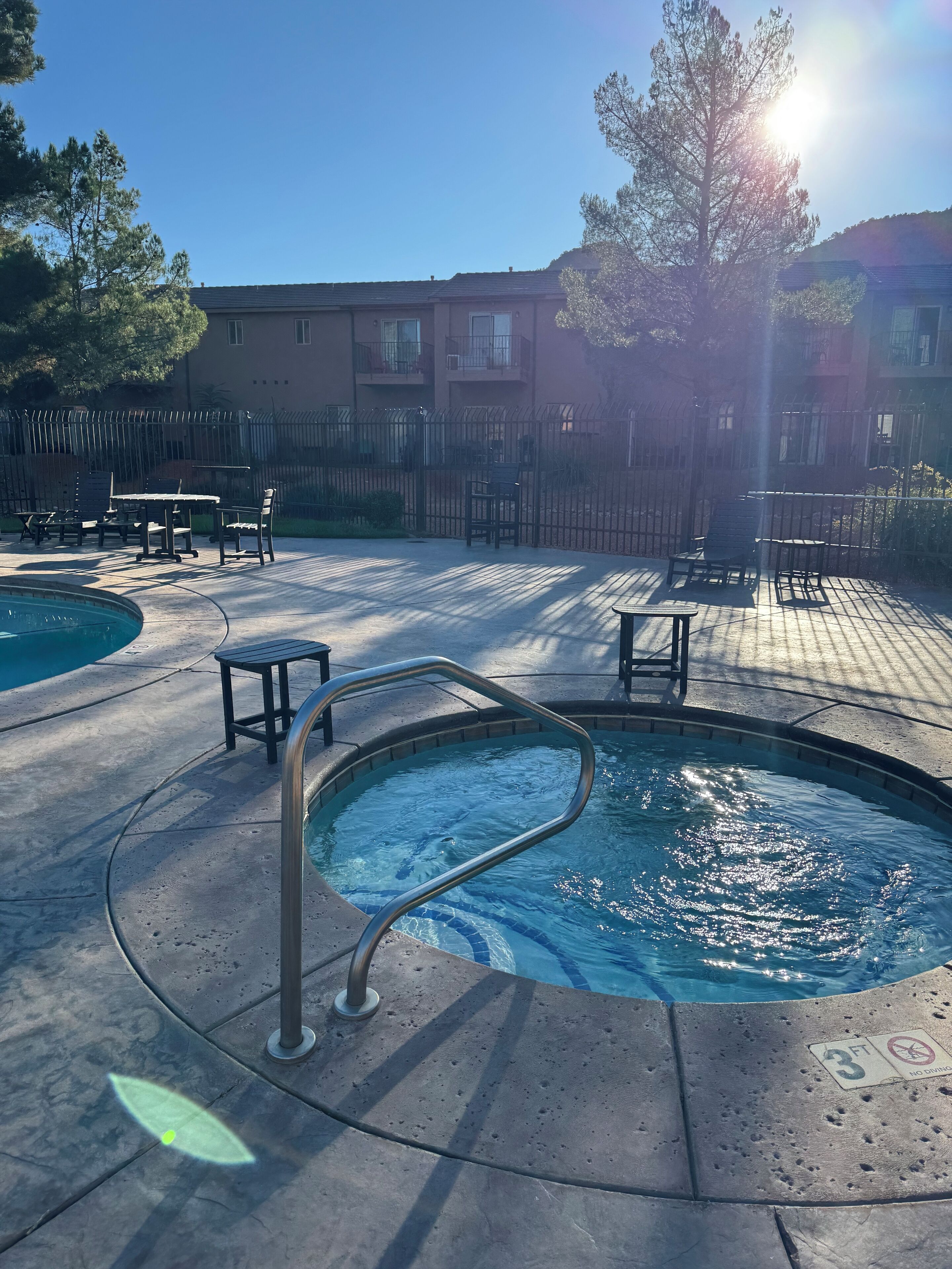 A swimming pool area with a metal ladder, lounge chairs, and a table.