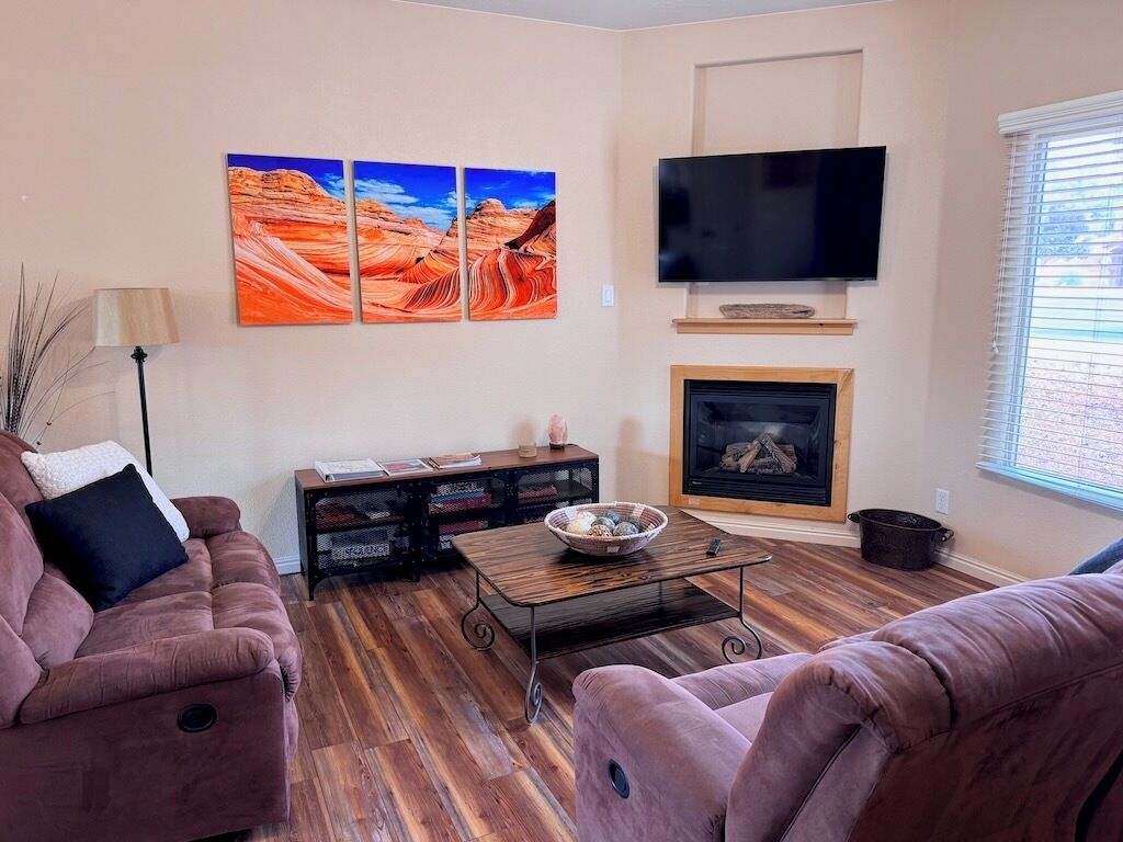 Un salon doté d’une cheminée, d’un téléviseur à écran plat et de deux grandes peintures représentant un paysage de canyon.