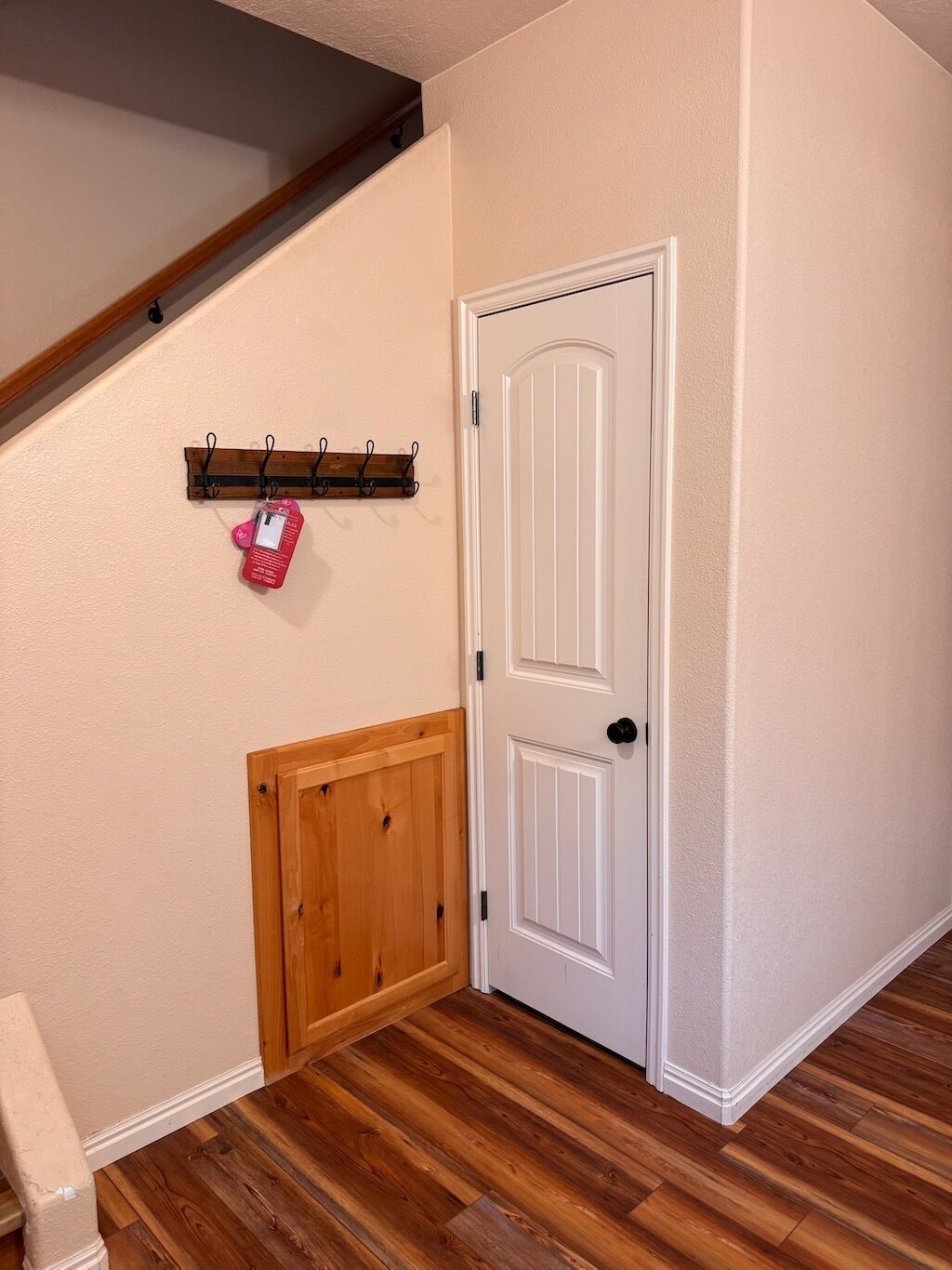 A hallway with a wooden door, a coat rack with a tag, and a wooden bench.