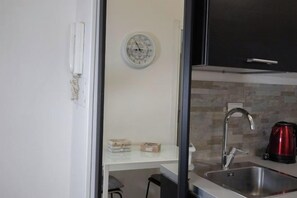 Eine Küche mit einem Spülbecken, einer Uhr und einem roten Wasserkocher.