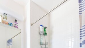 A bathroom with a white bathtub, a shower area, a vanity with a mirror, and a towel rack. - Charming 1-bedroom apartment in Brooklyn with Projector, 25 mins to Manhattan (Brooklyn)
