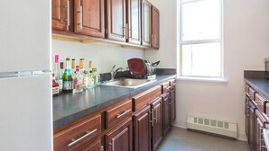 A kitchen with wooden cabinets, a sink, and a window. - Charming 1-bedroom apartment in Brooklyn with Projector, 25 mins to Manhattan (Brooklyn)