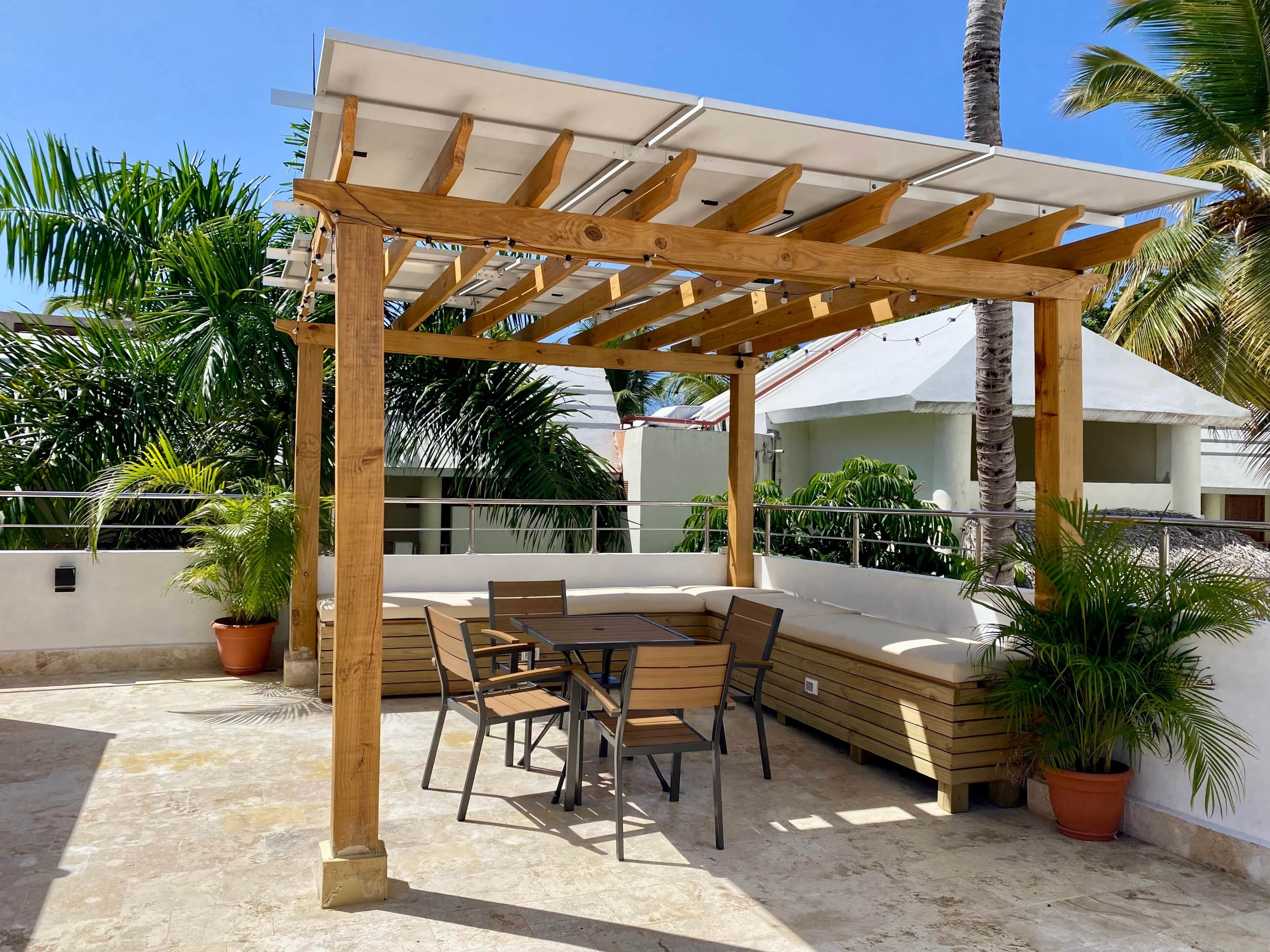 A covered outdoor seating area with wooden furniture and potted plants.