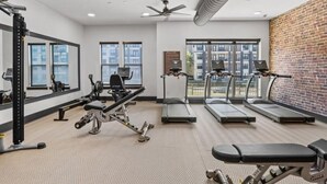 Una palestra con tapis roulant, macchinari per pesi e uno specchio.