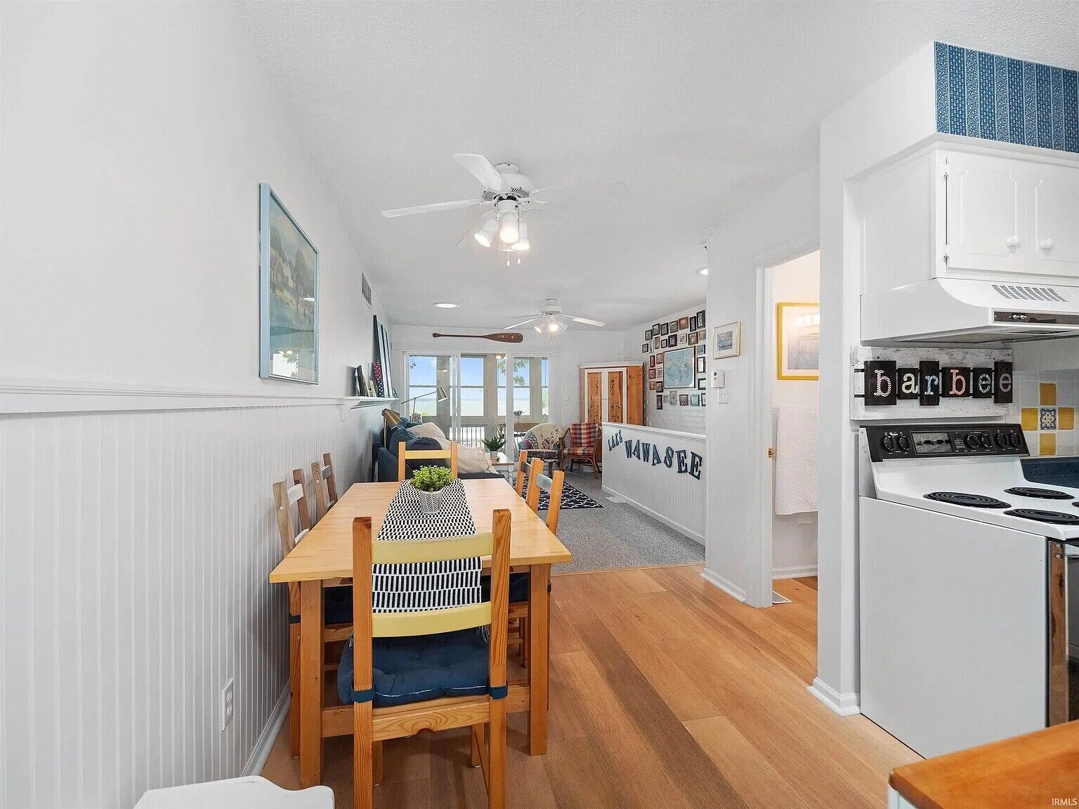 A modern kitchen with white cabinets, a stove, and a dining area with a wooden table and chairs.