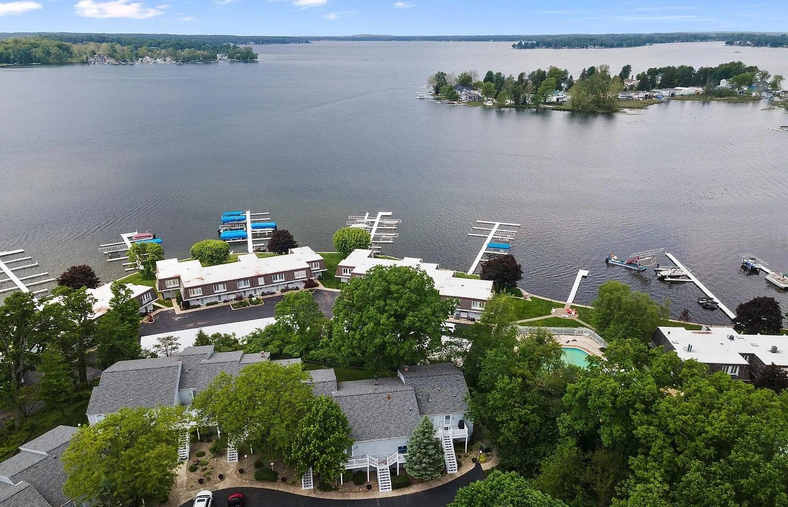 A lakeside property with a dock, boats, and a swimming pool.