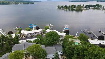 A lakeside property with a dock, boats, and a swimming pool.