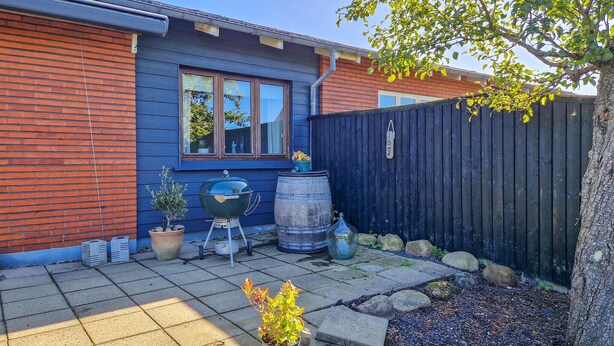 A backyard with a barbecue grill, potted plants, and a wooden fence.