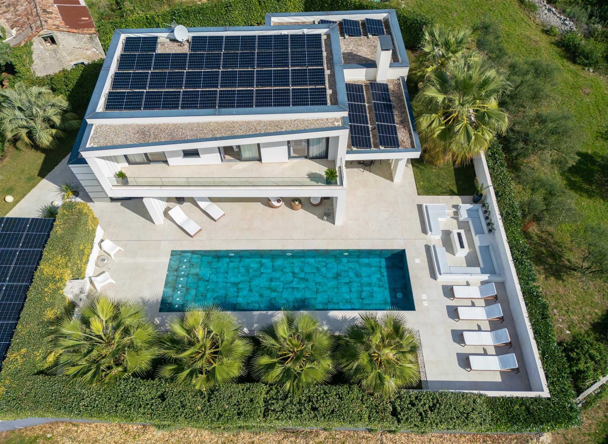 A modern two-story house with a swimming pool, solar panels, and a well-maintained garden.