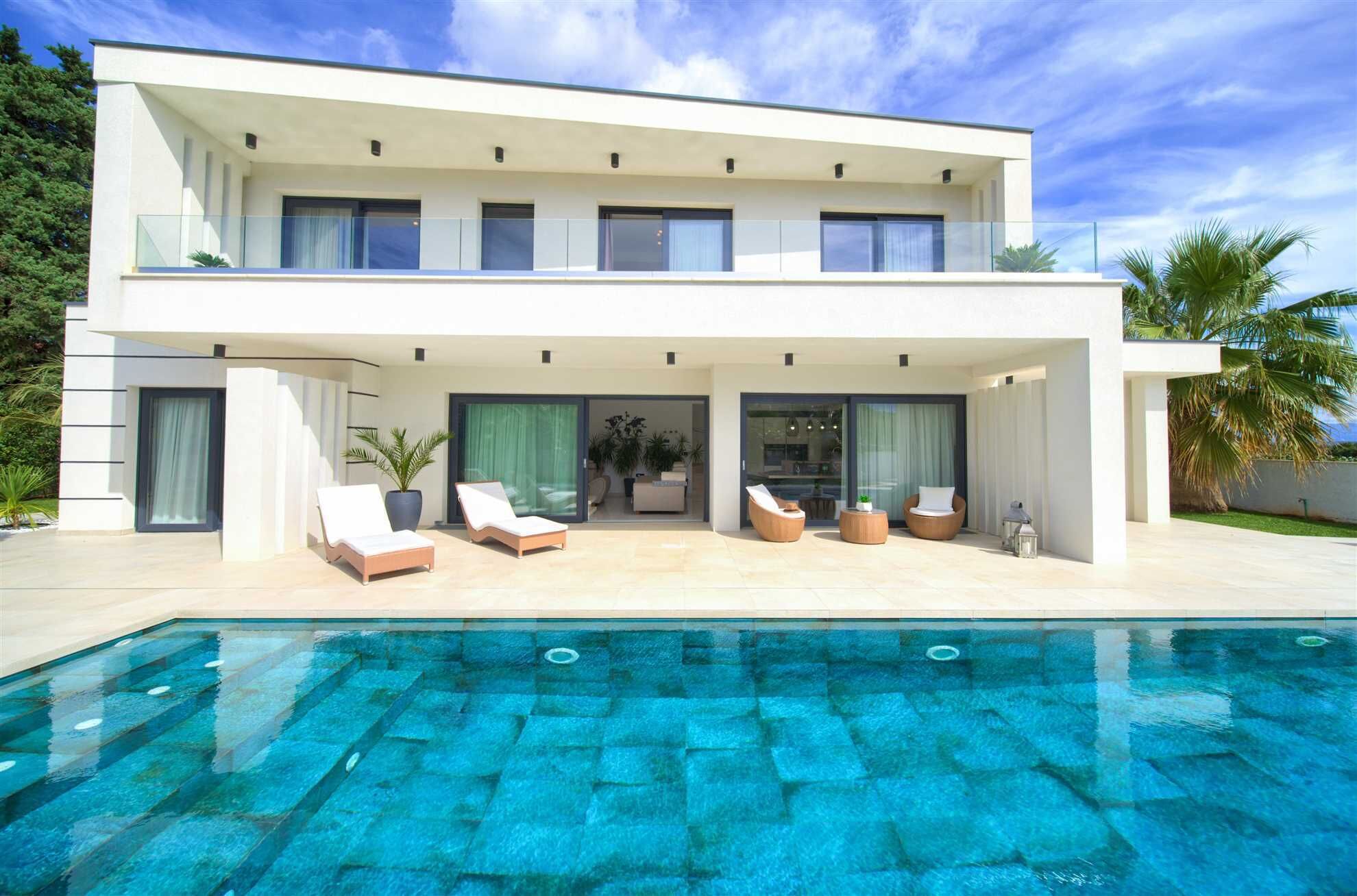 Une maison moderne à deux étages avec une piscine à l’avant.