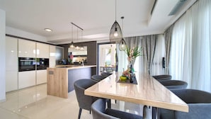 A modern kitchen with a central island, dark cabinets, and a dining area with a marble table and grey chairs. - Villa LUMINOSA with outdoor and indoor pool and sauna (Vrh)