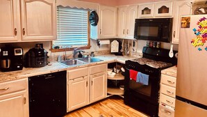Una cocina con armarios blancos, un microondas negro y un refrigerador de acero inoxidable.
