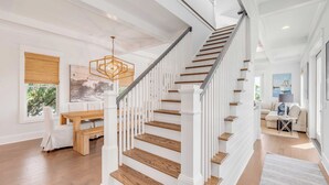Una escalera de madera con barandillas blancas que lleva a un rellano con un banco y una mesa.