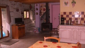 A rustic kitchen with a stone wall, wooden furniture, and a tiled backsplash.