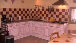 A kitchen with a checkered backsplash, a gas stove, and various utensils hanging above the counter. - La Grange du Riou, superb scenery, pastoral setting at 1680 metres (Grust)