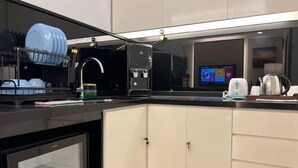 Een moderne keuken met een vaatwasser, koffieapparaat en een televisie op de achtergrond.