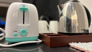 Een keuken met een witte en teal-kleurige broodrooster, een bruin dienblad en een roestvrijstalen waterkoker.