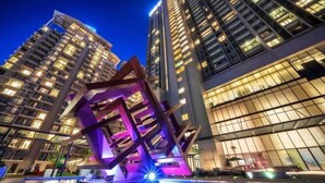 Een modern hotel met een opvallende geometrische sculptuur in de binnenplaats, omringd door hoge gebouwen met verlichte ramen.