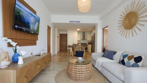 Een moderne woonkamer met een televisie, bank, salontafel en decoratieve objecten.