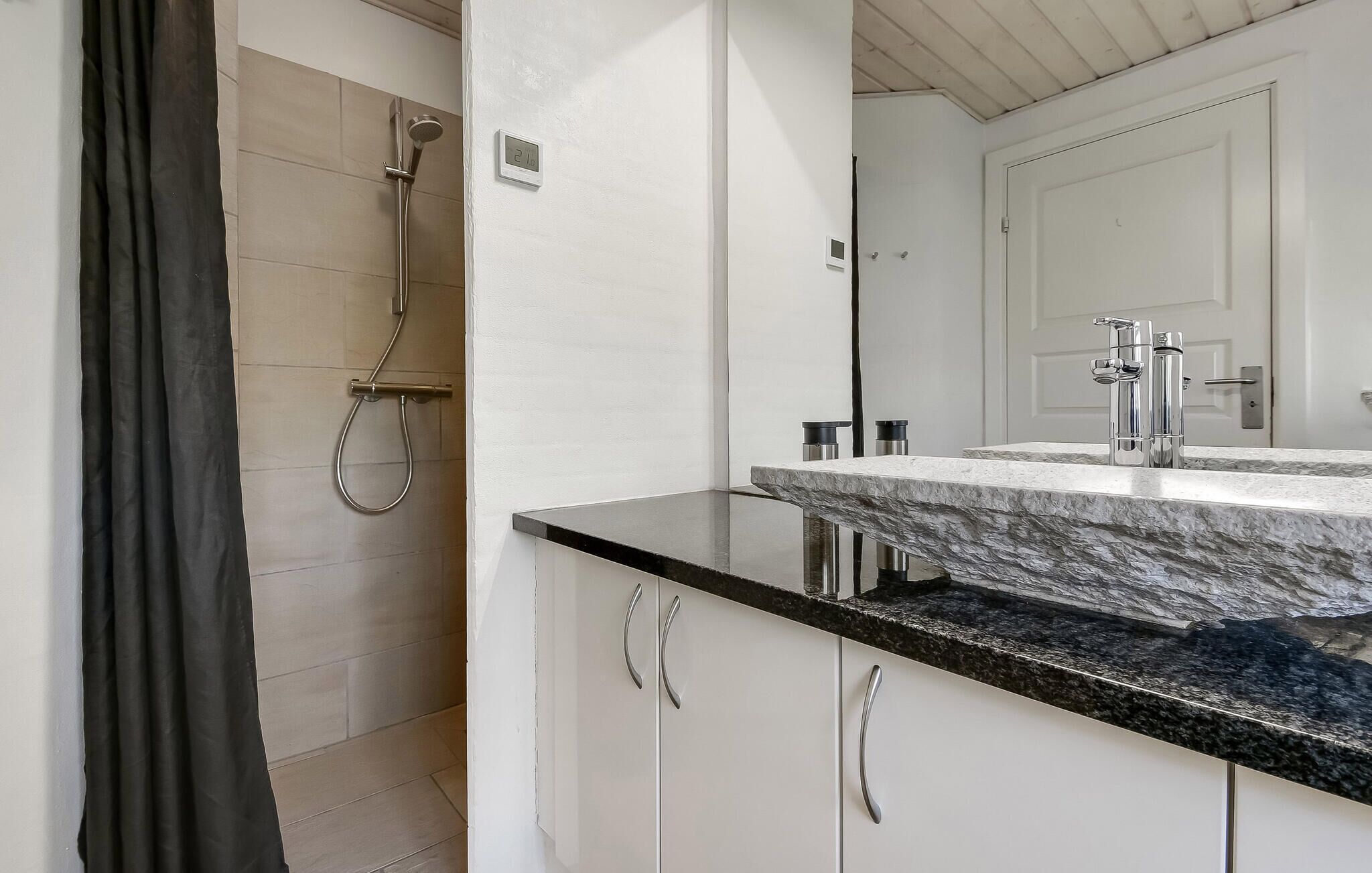 A bathroom with a shower, a sink with a marble countertop, and a mirror.
