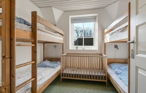 A dormitory room with bunk beds, a window with a view of trees, and a small bedside table with a plant. - Nice home in Ulfborg with sauna (Ulfborg)