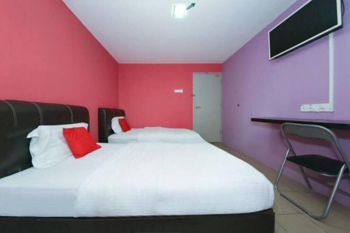 A room with two beds, a desk, and a chair.