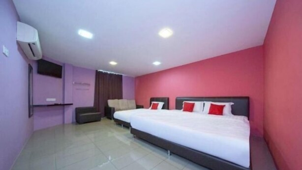 A hotel room with a large bed, a flat-screen TV, and a seating area with a sofa and a small table. - Hotel Inn (Durian Sebatang)