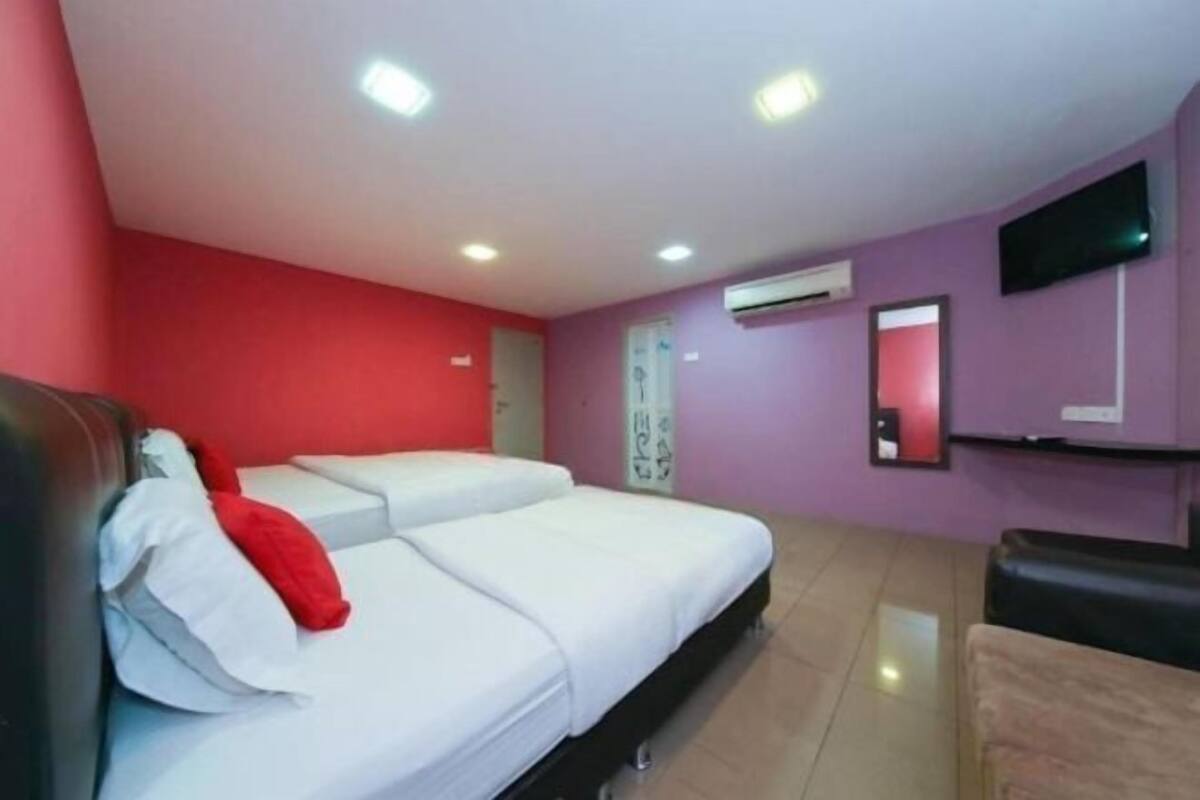 A hotel room with a bed, a TV, and an air conditioning unit.