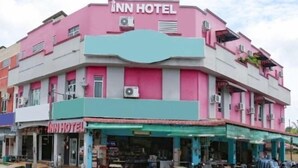 A multi-story building with a pink and teal facade, featuring an 'Inn Hotel' sign on the top. - Hotel Inn (Durian Sebatang)