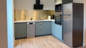 A modern kitchen with grey cabinets, a stainless steel refrigerator, a built-in oven, and a microwave. - Country house in the heart of the Parc des Volcan, 10 minutes from Clermont-Ferrand (Romagnat)