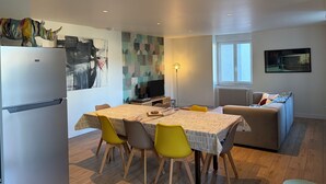 A modern kitchen with a refrigerator, dining table, chairs, and a sofa. - Country house in the heart of the Parc des Volcan, 10 minutes from Clermont-Ferrand (Romagnat)