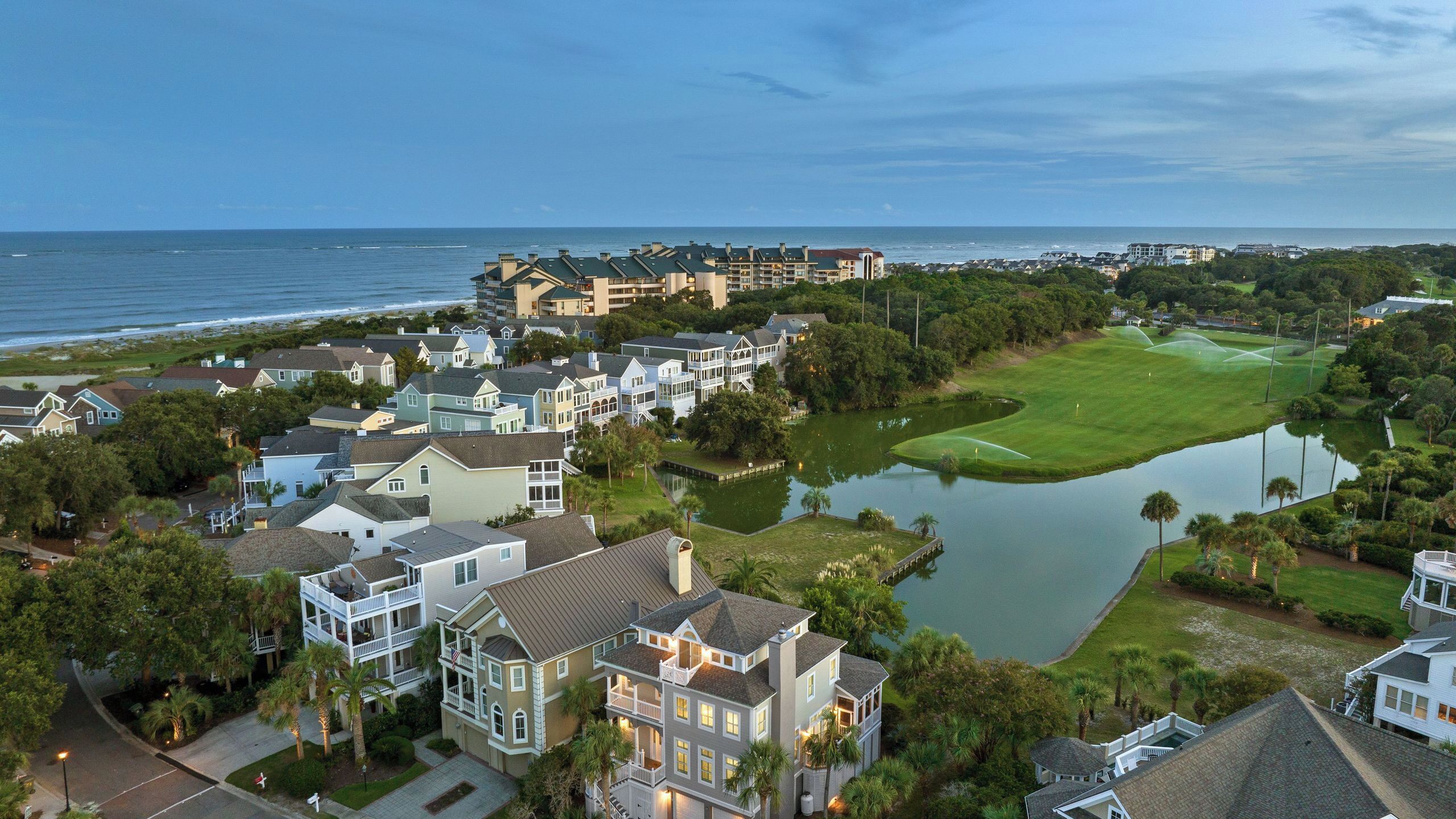 A coastal residential area with houses, a golf course, and a body of water.