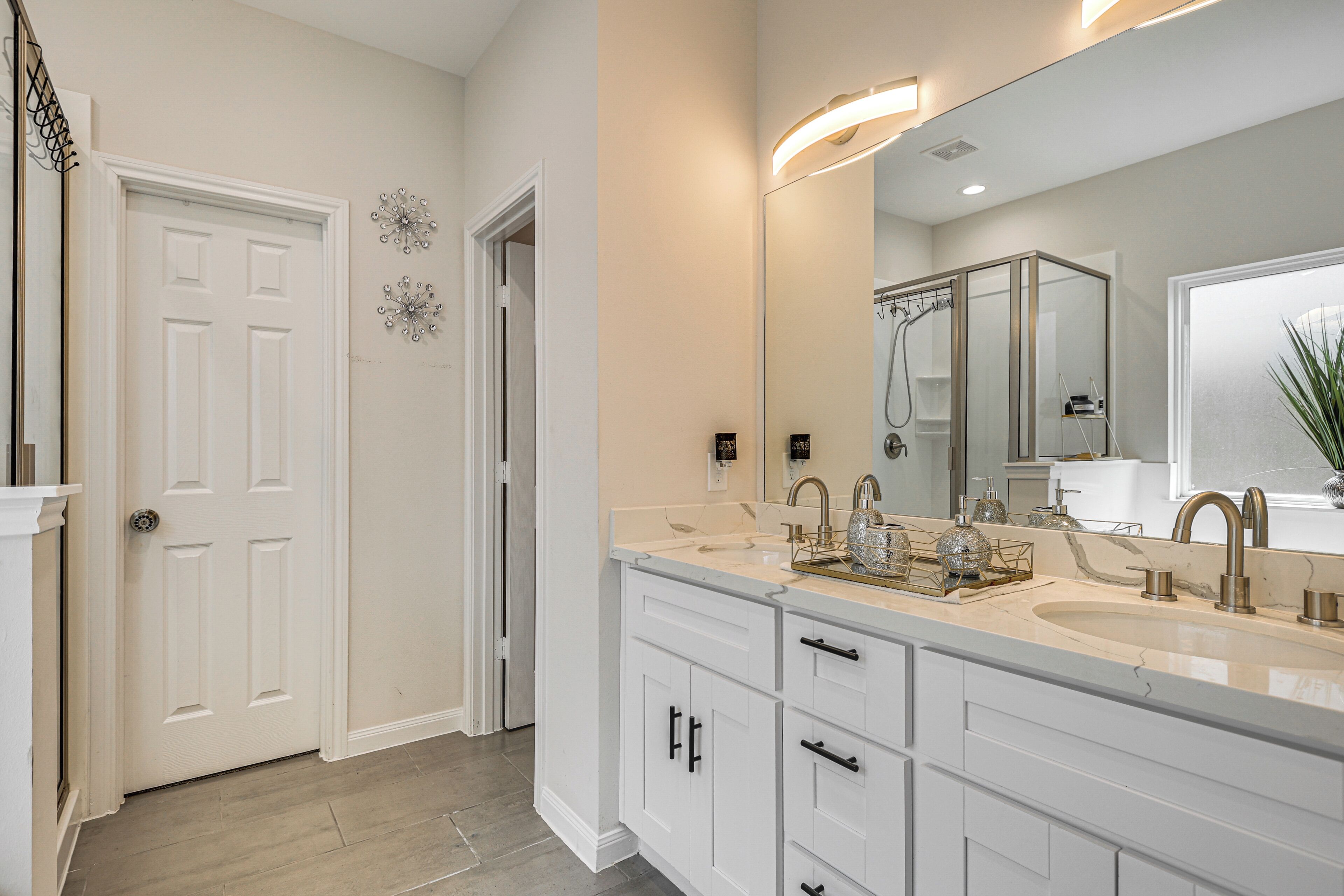 Une salle de bain moderne avec un grand miroir, deux lavabos et un espace douche.