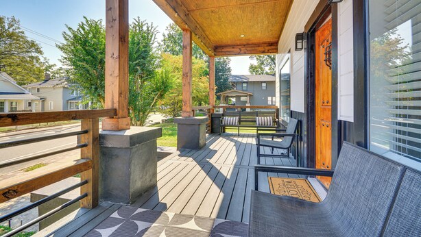 Una terraza de madera con asientos al aire libre, un felpudo y una puerta con ventanal.