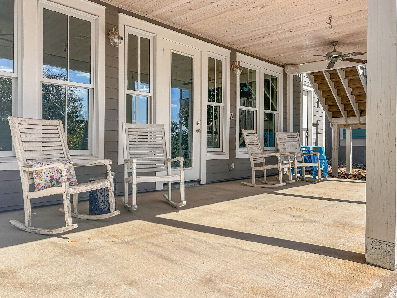 A covered porch with rocking chairs and a staircase.