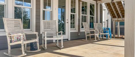 A covered porch with rocking chairs and a staircase.