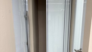 A narrow hallway with a sliding glass door leading to a room. The hallway has tiled flooring and a beige wall. - Caleno Boricua apartment. Modern luxury apartment 5 minutes from the beach (Quebradillas)