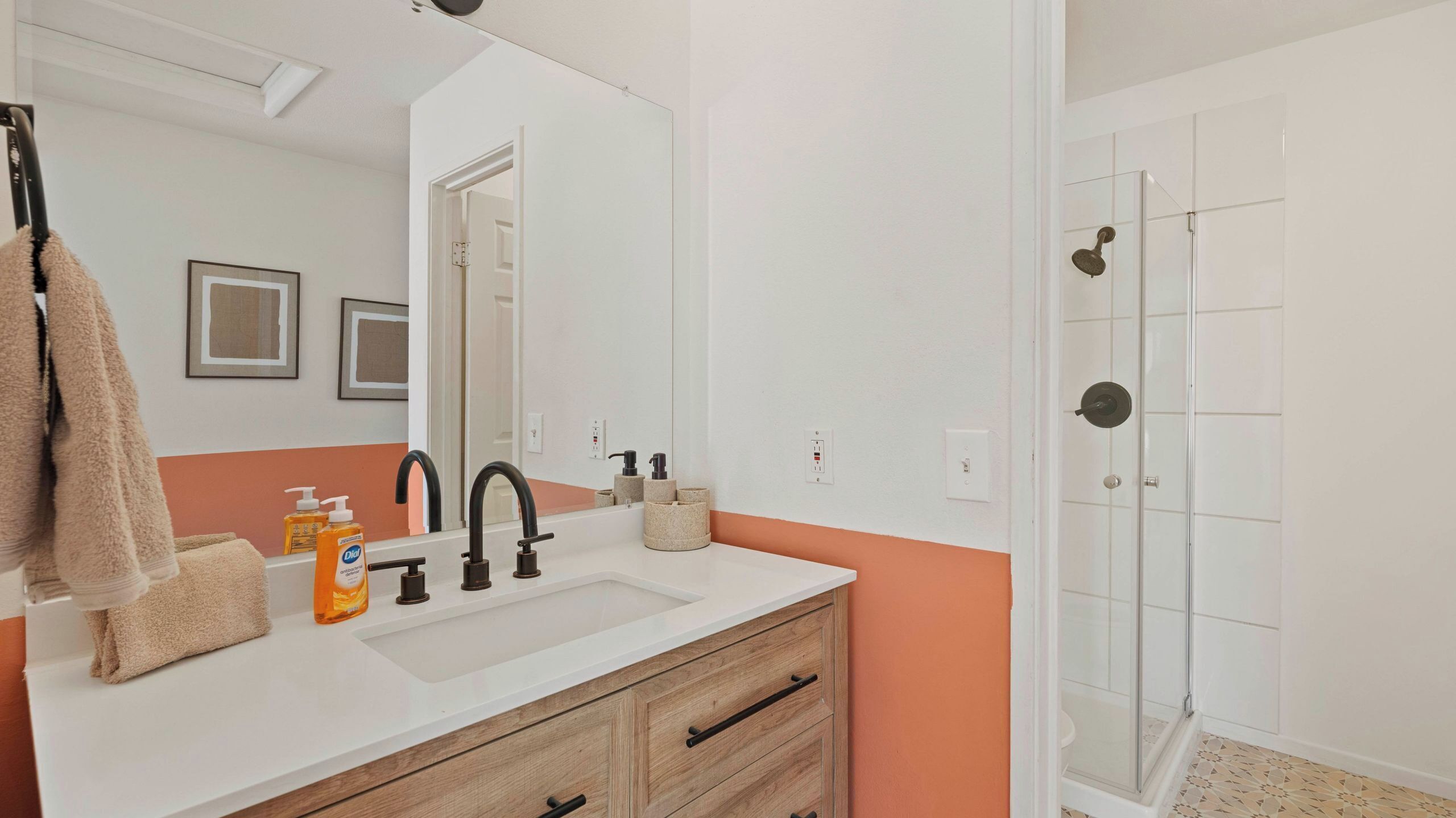 A bathroom with a white sink, black faucets, a mirror, and a shower area.